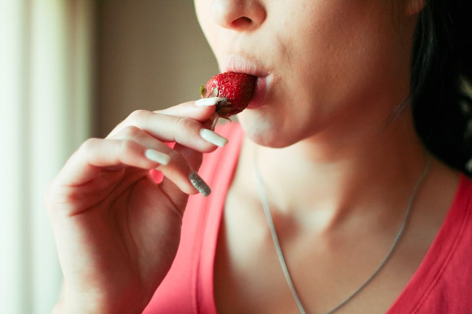 Kvinna äter jordgubbe